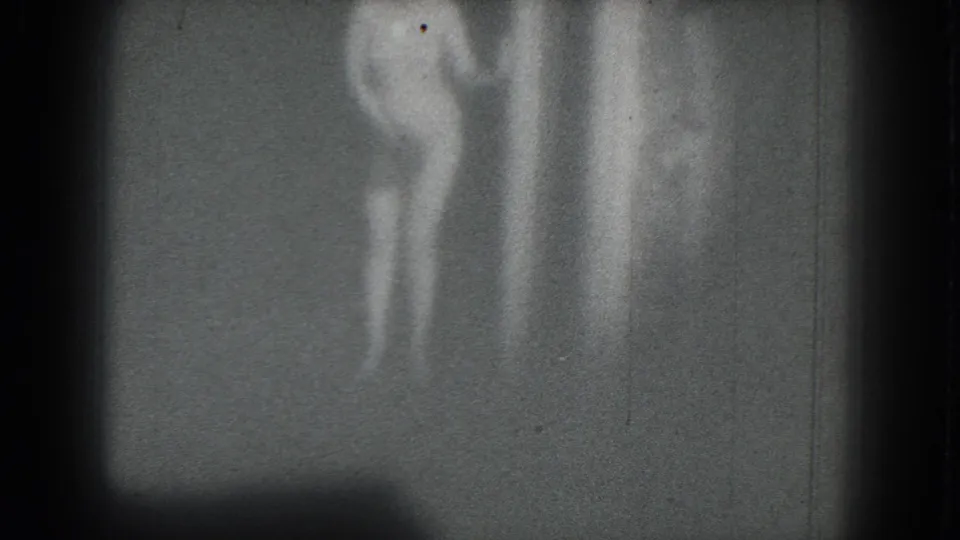 Soft 1975 8mm frame from San Francisco showing a woman in a two-piece bathing suit dancing in low light.