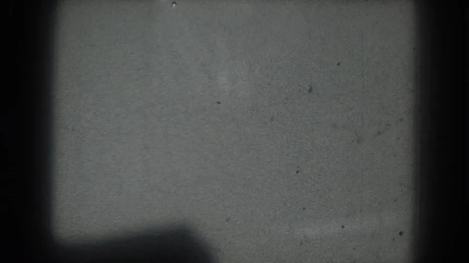 Obscured 1975 San Francisco 8mm frame showing a dim stage-like field with dark bands and little readable subject detail.