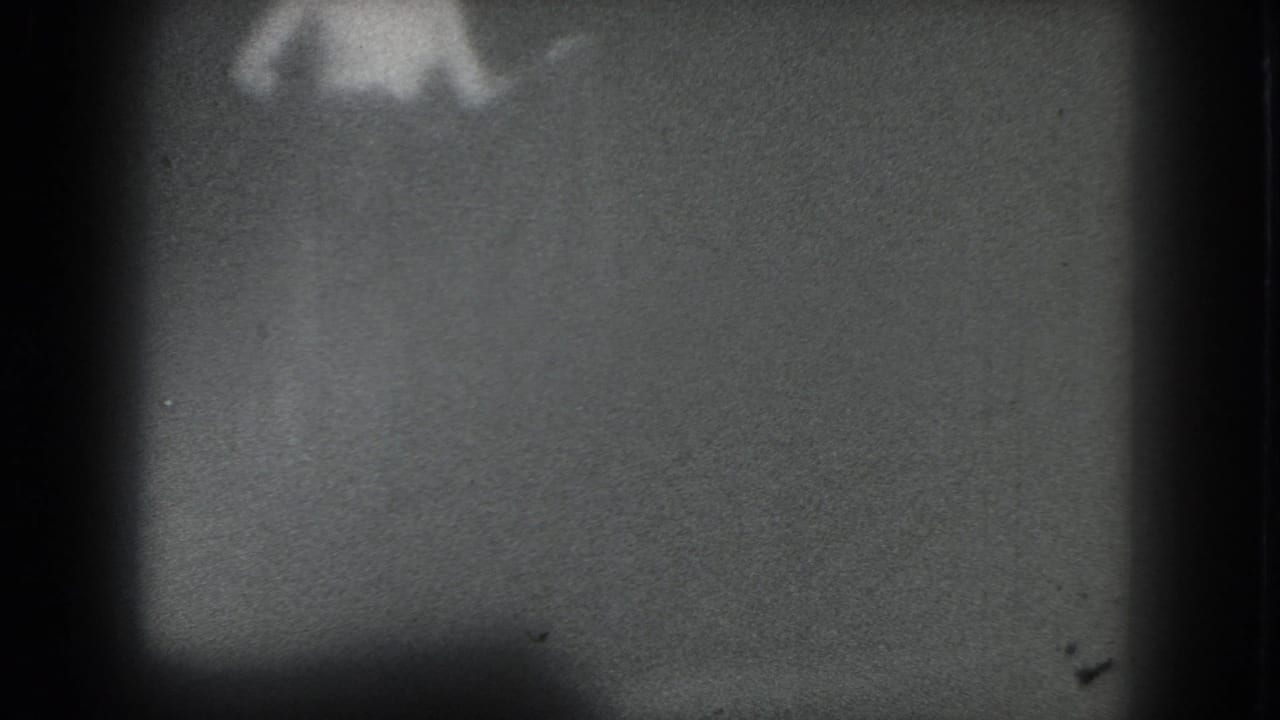 Very blurred performer form at the top of a grainy gray frame with dark borders.