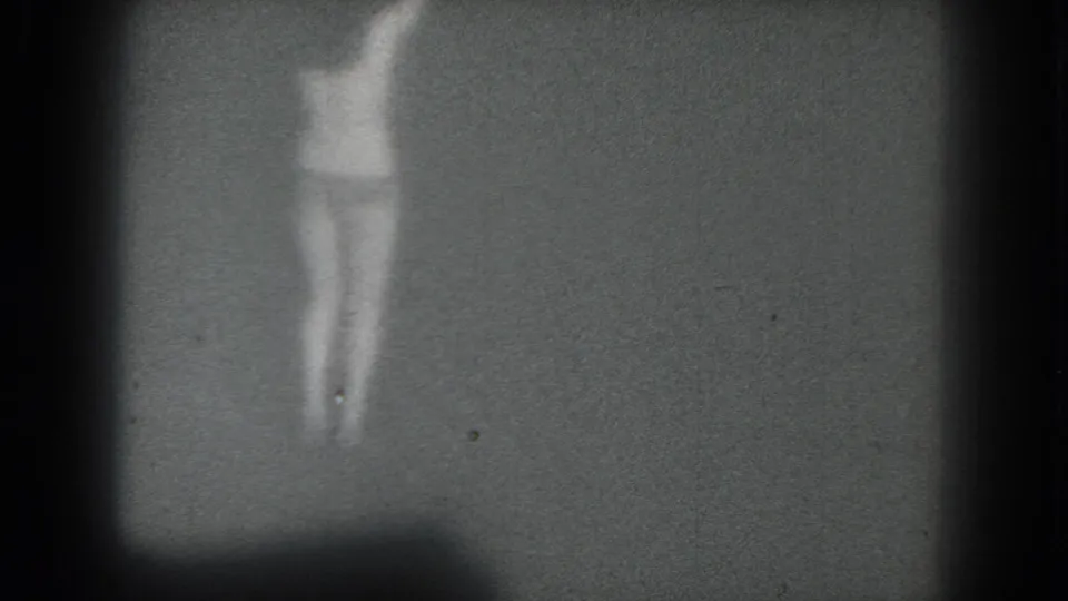 A final 1975 San Francisco 8mm frame shows the dancer as a pale, blurred figure centered against the dim stage backdrop.