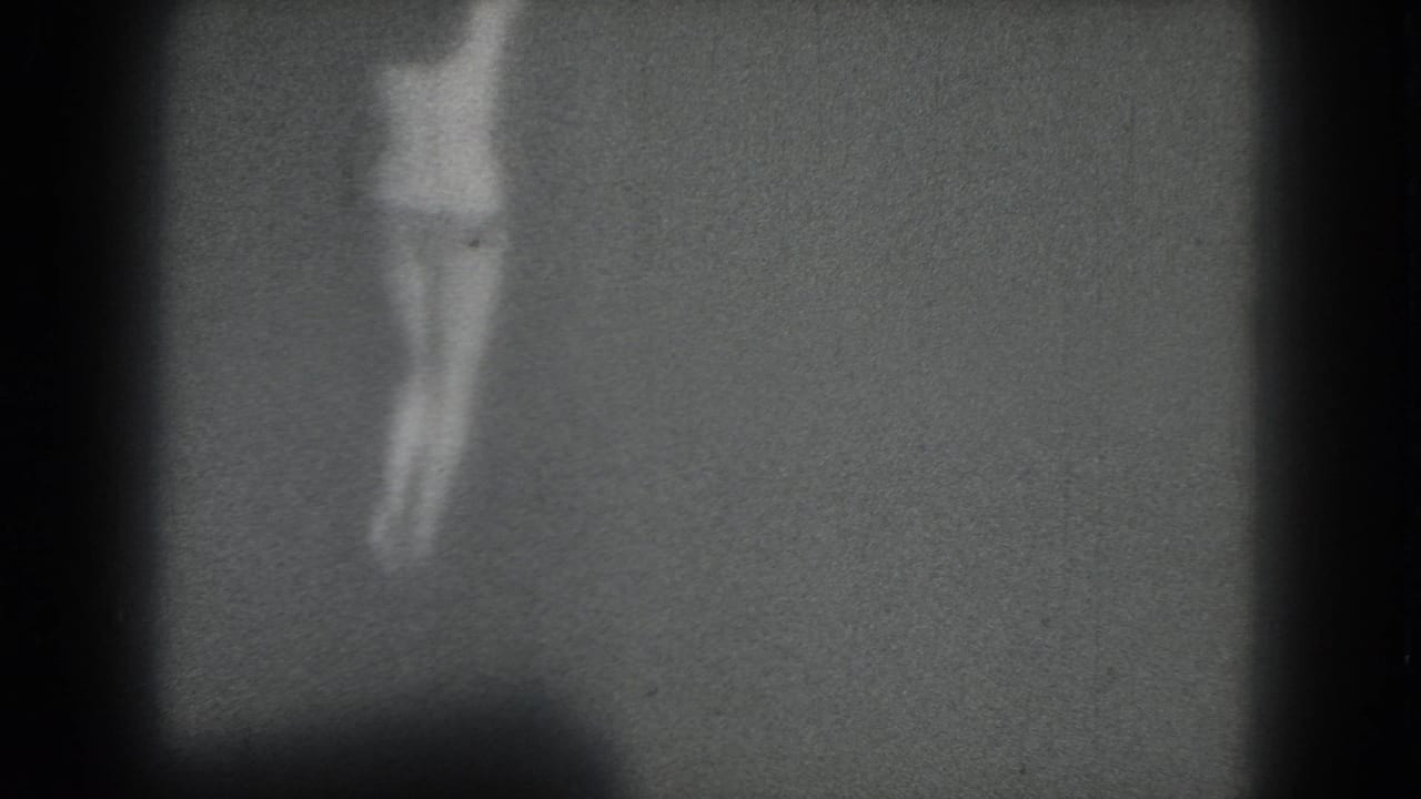 Blurred woman with legs crossed or turning in a dim frame.