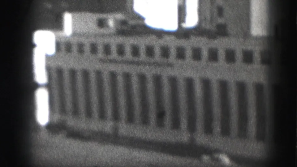 1975 Harrisburg frame showing a blurred downtown office building, bright edge highlights, and pronounced 8mm grain.