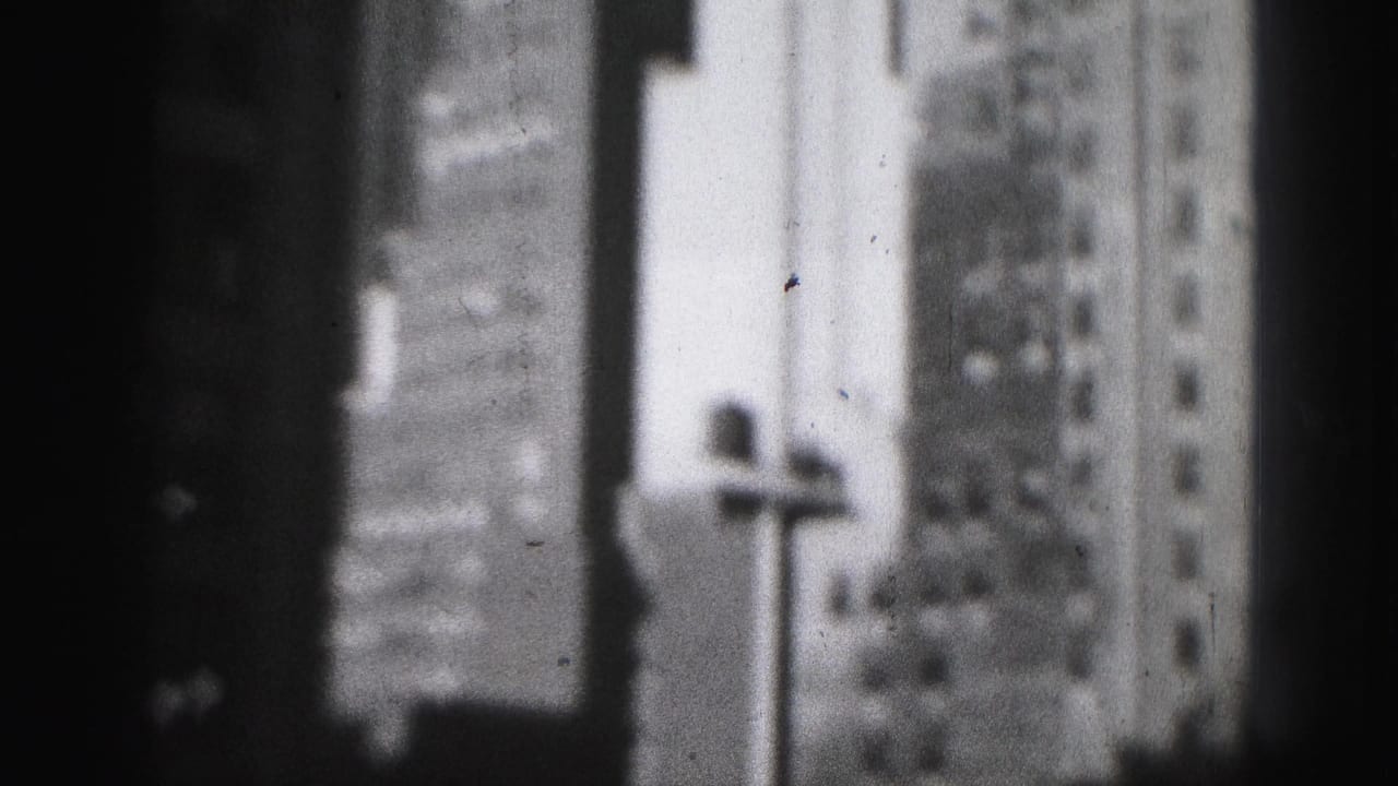 Blurred skyscraper facades and a streetlamp shape beside a dark vertical foreground edge.