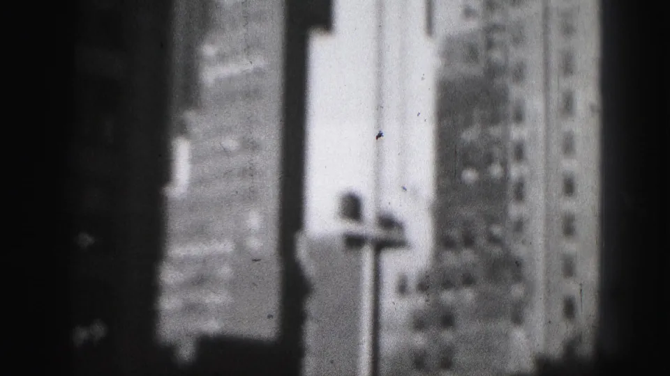 A soft 8mm view of Harrisburg skyscraper facades with a streetlamp shape in the foreground and dark framing at left.