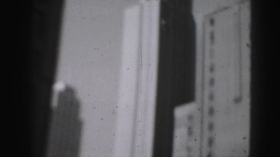 Soft black-and-white 8mm view of Harrisburg high-rises, with a dark foreground band and pale building surfaces filling the frame.