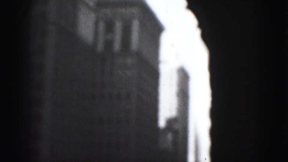 1975 8mm frame showing a bright overexposed building edge against a dark Harrisburg urban facade.