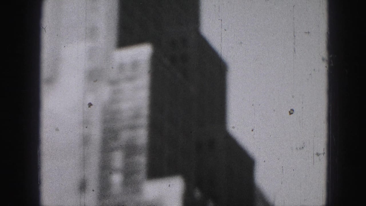 Vertical window mullion divides shadowed high-rise shapes and a pale background.