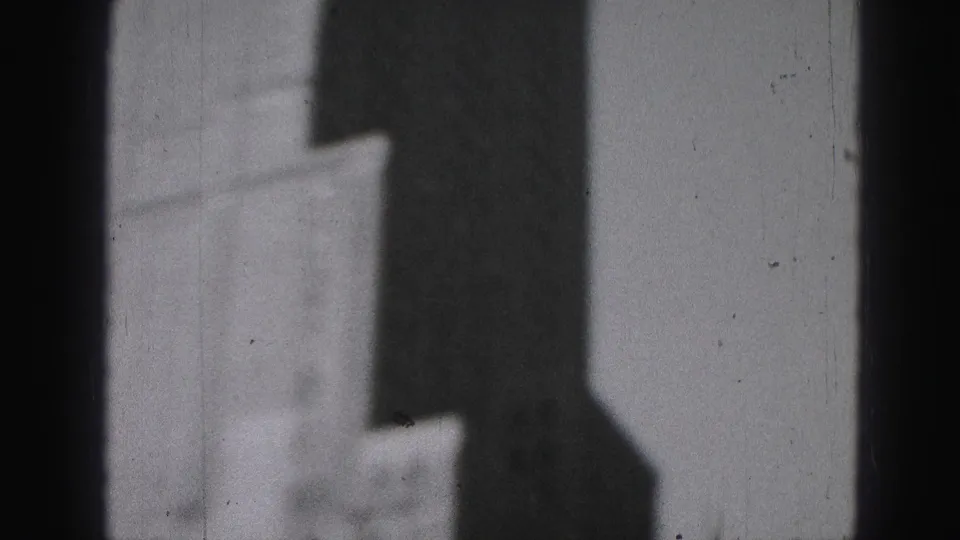 1975 Harrisburg frame showing a dark structural edge, window framing, and a blurred downtown building beyond.