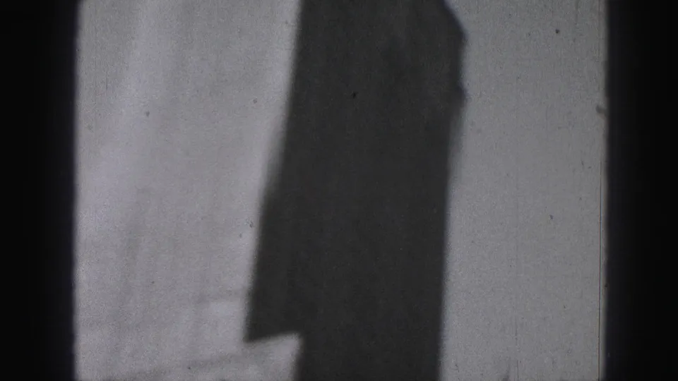 Final 8mm frame from the Harrisburg view with a dark window bar and shadowed high-rise form against bright sky.