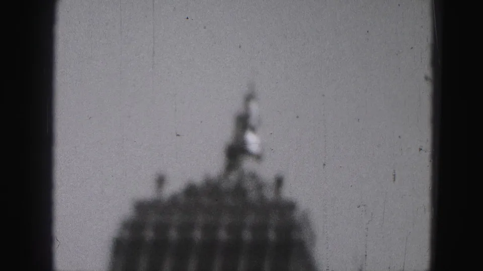 1975 Harrisburg 8mm frame with a blurred tower crown and small spire partly framed by a dark vertical foreground shape.