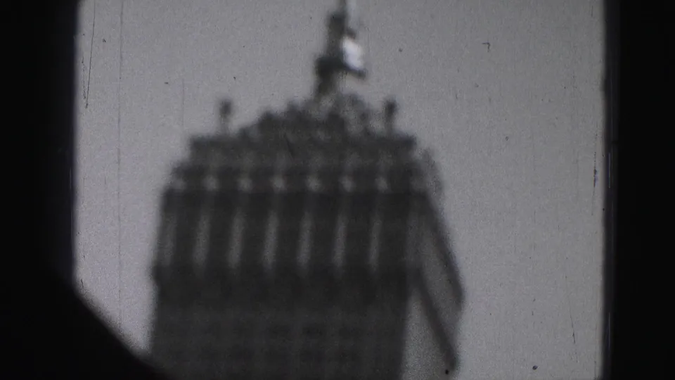 1975 Harrisburg frame showing a blurred high-rise roofline with a small spire, bordered by dark 8mm frame edges.