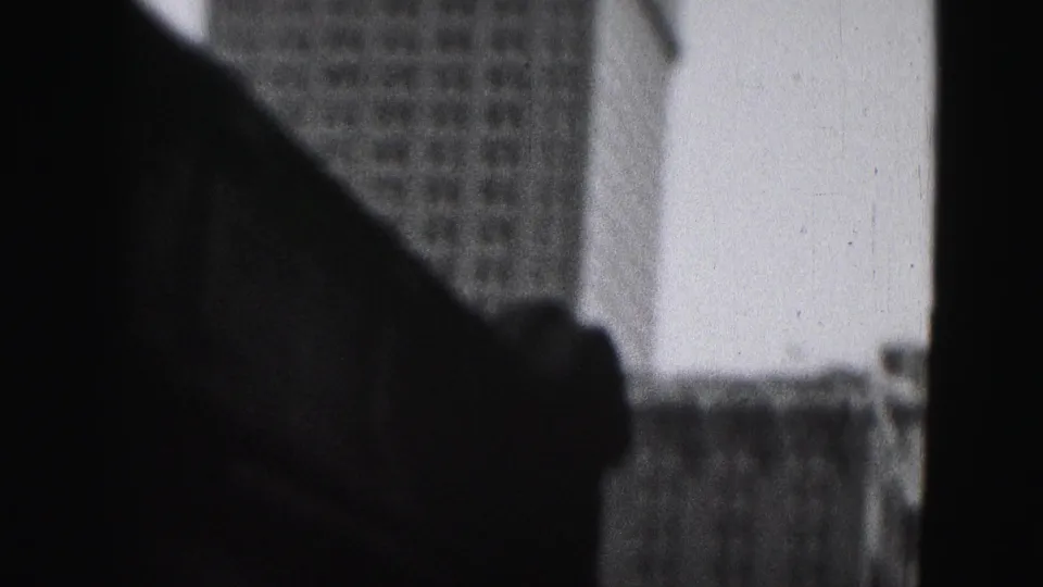 A 1975 Harrisburg home-movie frame shows dark window or vehicle framing with office buildings partly visible beyond it.