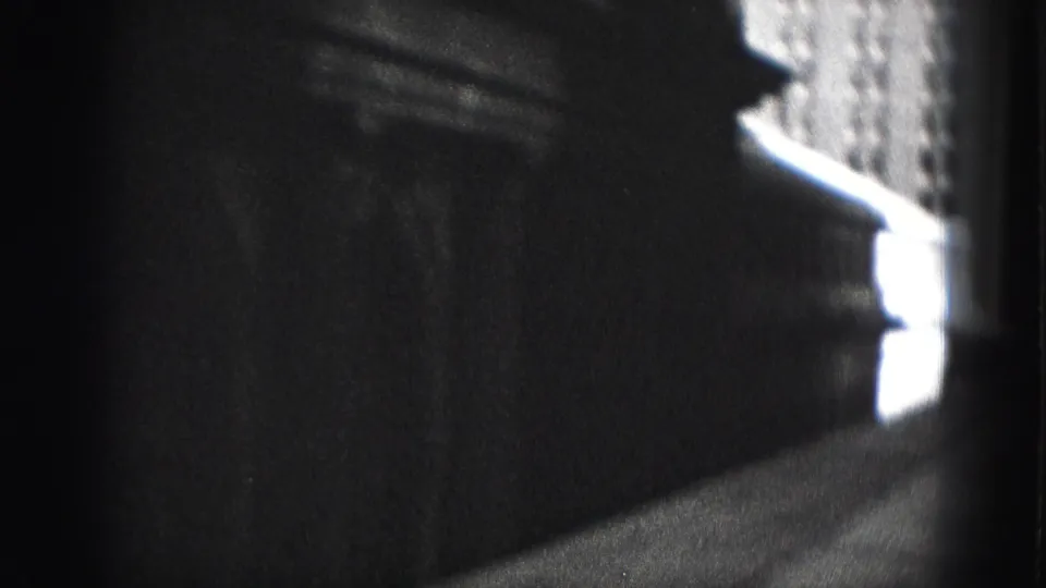 The moving camera passes close to a dark building wall, with a narrow walkway and bright exterior detail ahead in Harrisburg.