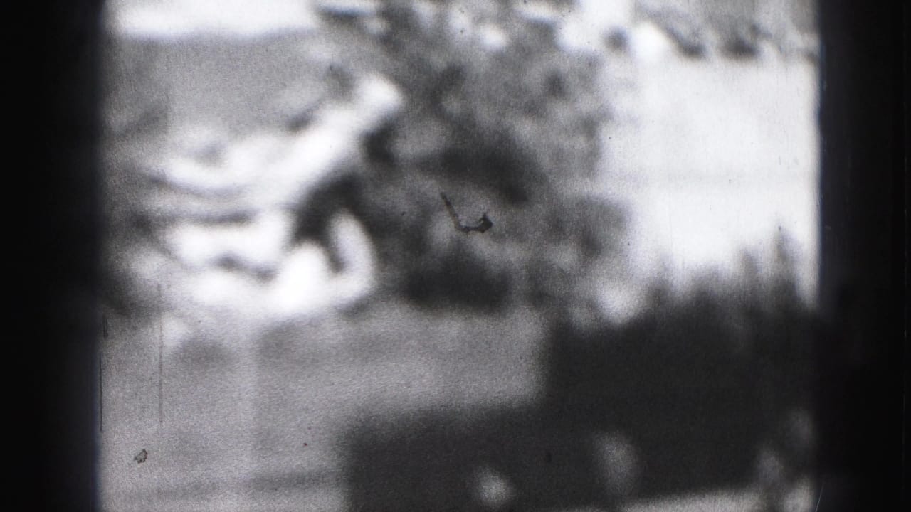Very soft view of an outdoor skating rink with blurred figures and dark film edges.