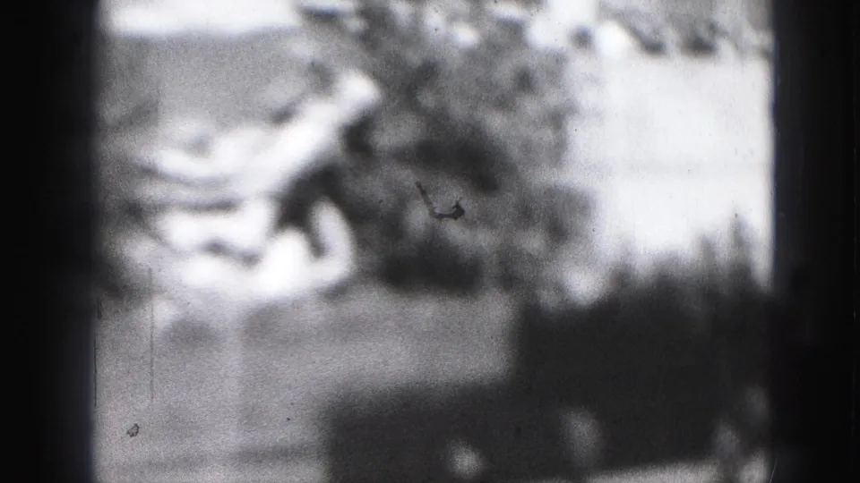 Soft 1975 8mm frame from Harrisburg showing indistinct skaters on an outdoor rink in daylight.