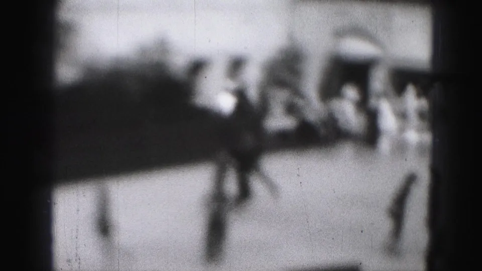 Unfocused Harrisburg rink view with skaters crossing the ice near a low barrier in daylight.