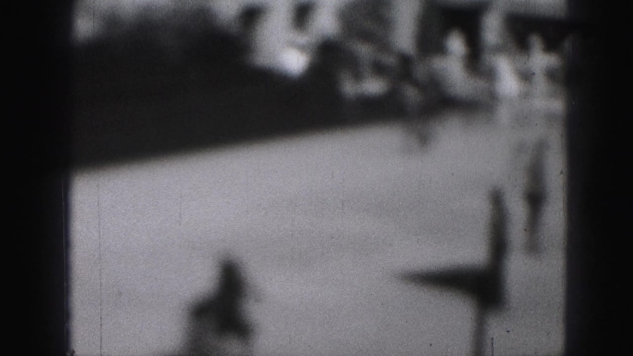 Black-and-white 8mm view of one indistinct skater moving across a bright public rink area in Harrisburg, Pennsylvania.