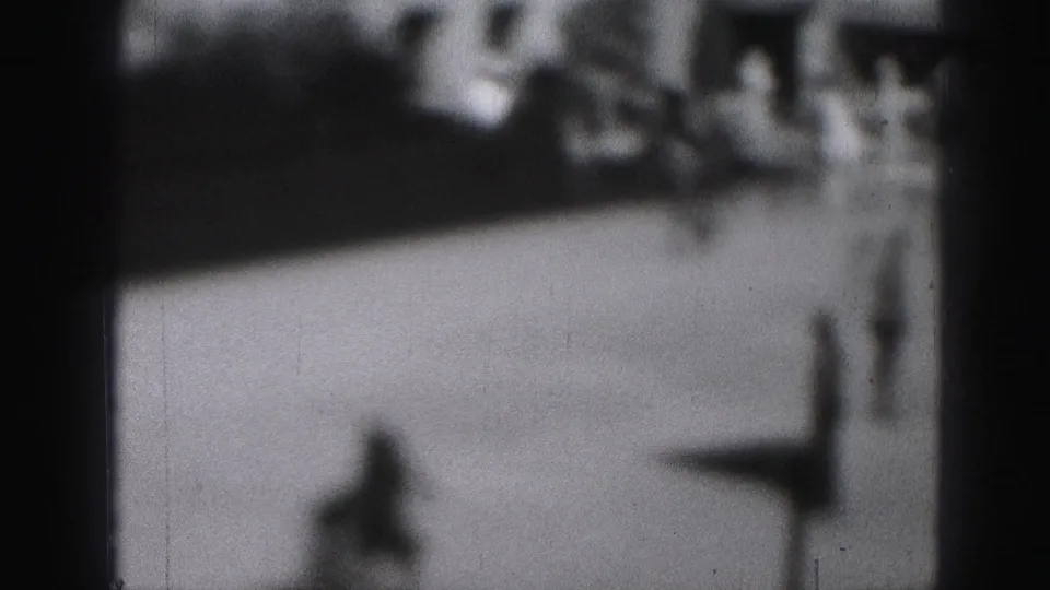 Black-and-white 8mm view of one indistinct skater moving across a bright public rink area in Harrisburg, Pennsylvania.