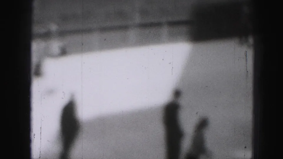 Soft 1975 8mm frame from Harrisburg showing silhouetted skaters spread across an outdoor ice rink.