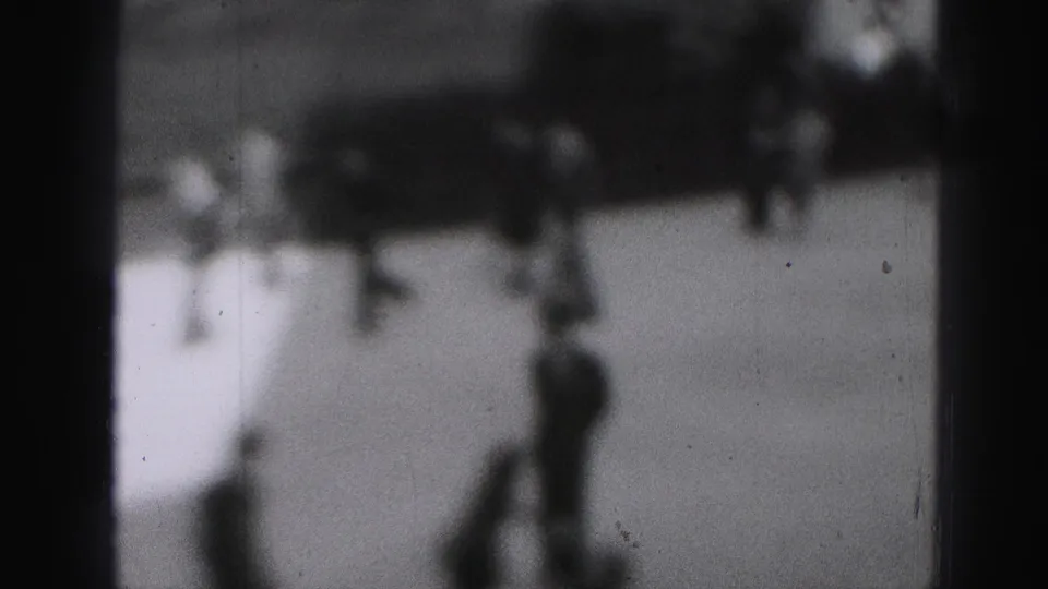 Black-and-white 8mm view of skaters on an outdoor Harrisburg rink, with soft focus and visible film wear.