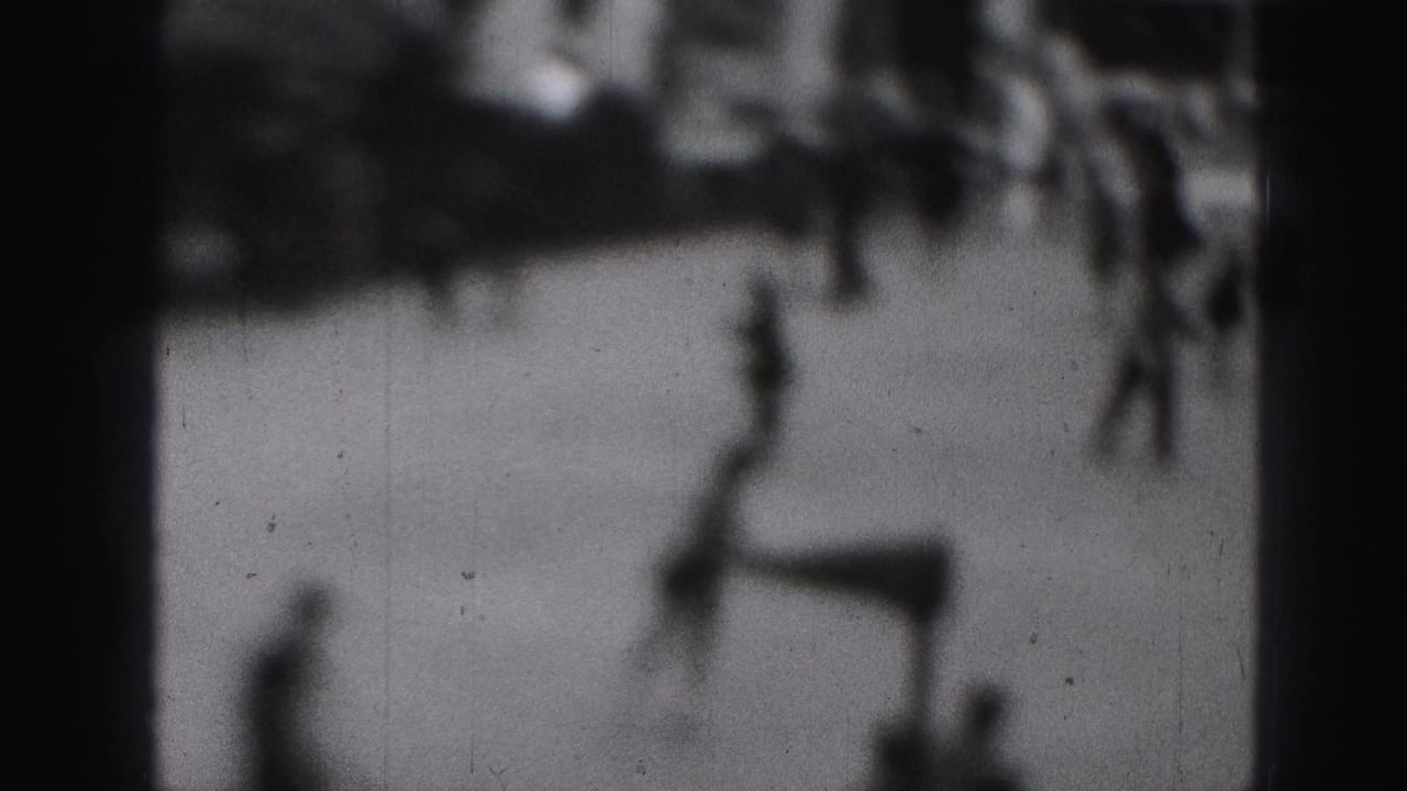 Soft-focus 1975 8mm frame from Harrisburg showing blurred people moving in an outdoor activity area.