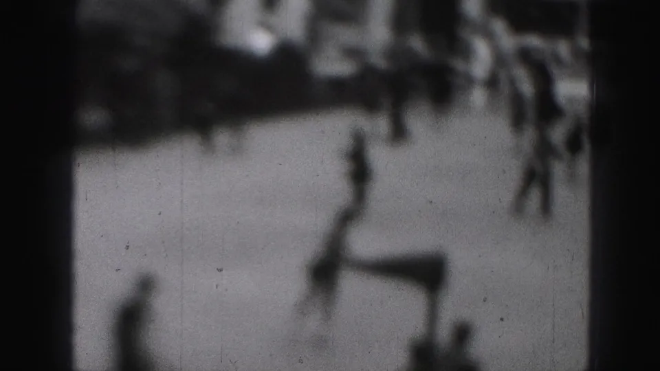Soft-focus 1975 8mm frame from Harrisburg showing blurred people moving in an outdoor activity area.