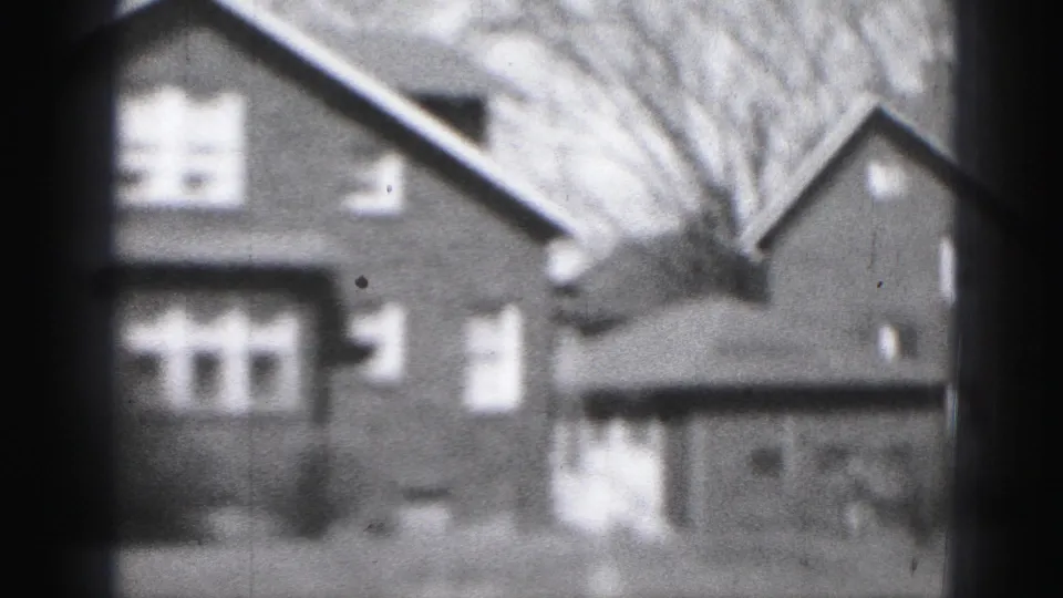 Soft 1975 Harrisburg 8mm frame showing a brick house and garage with windows, gabled roof, bare trees, and front yard.