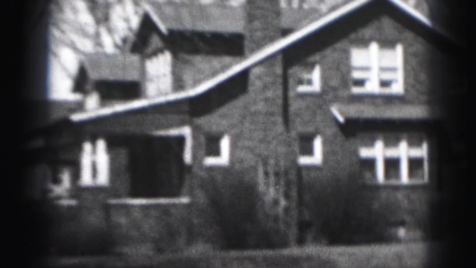1975 Harrisburg frame showing the brick house facade, upper windows, chimney, bare branches, and front lawn.