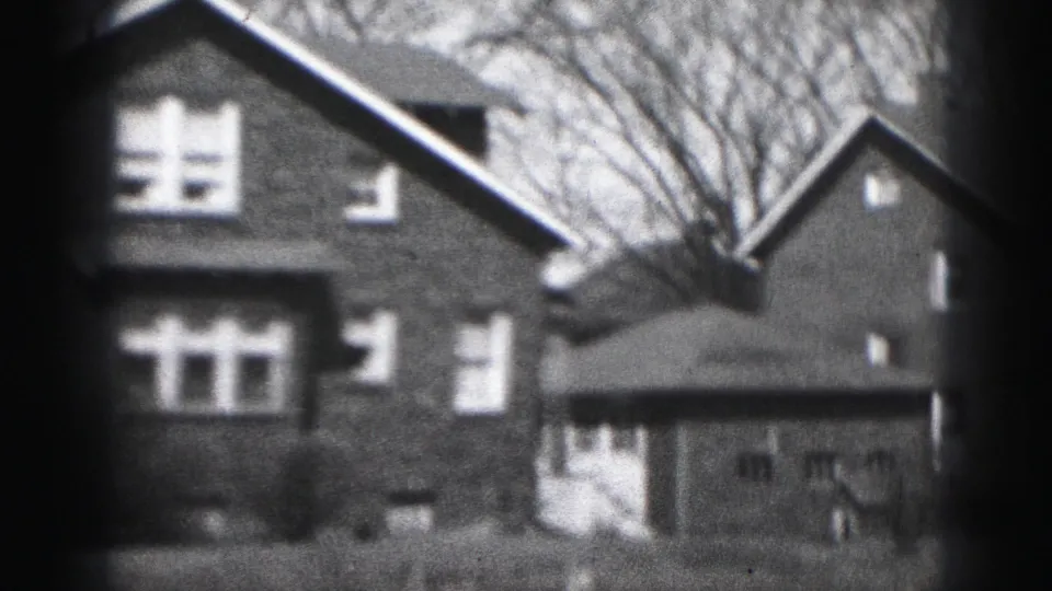 1975 Harrisburg frame showing the brick residence with front windows, side roofline, bare trees, lawn, and a garage-like structure.
