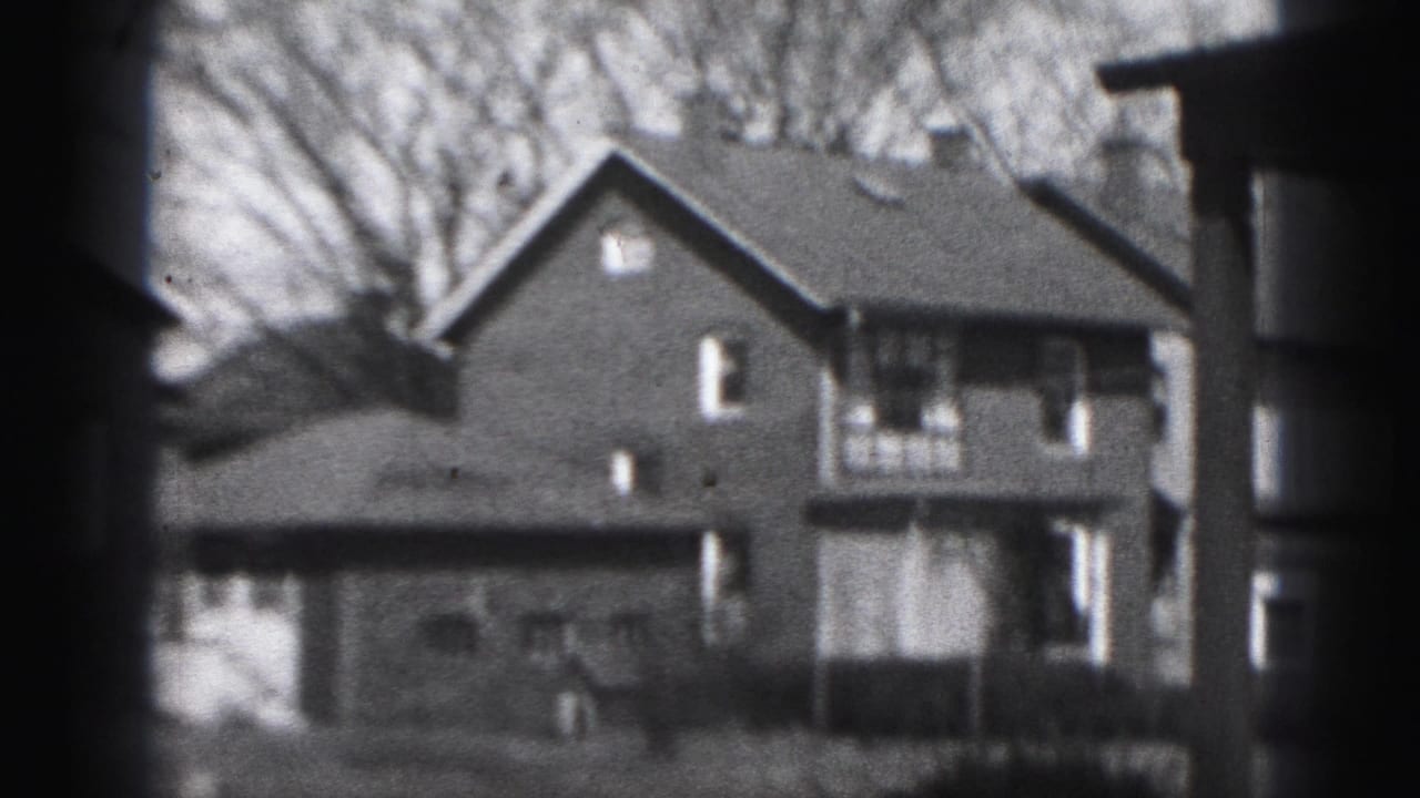A Harrisburg residential block appears in soft-focus 8mm, with brick houses, rooflines, windows, and leafless trees.