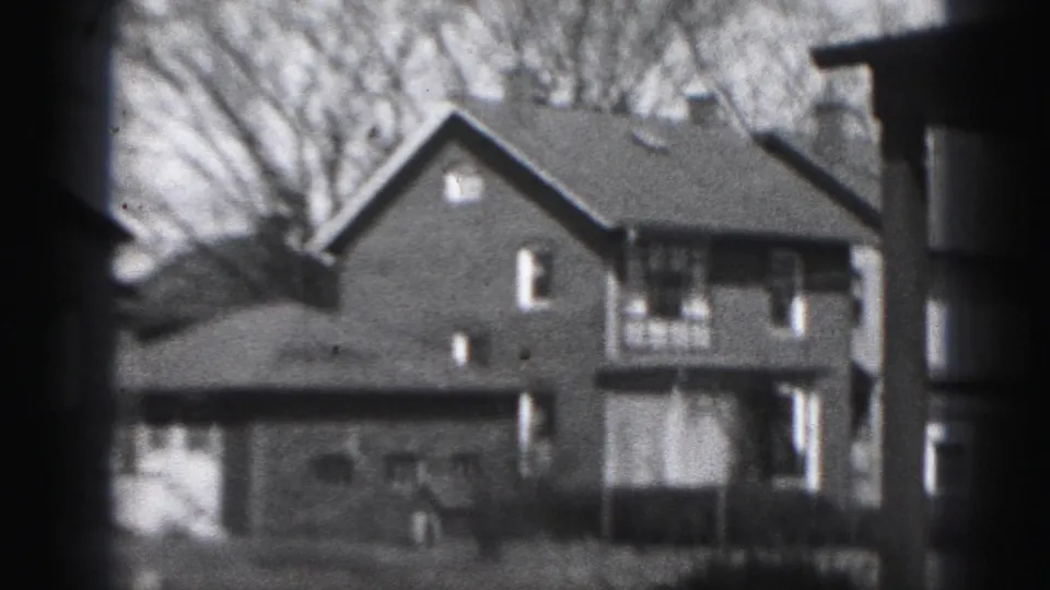 A Harrisburg residential block appears in soft-focus 8mm, with brick houses, rooflines, windows, and leafless trees.