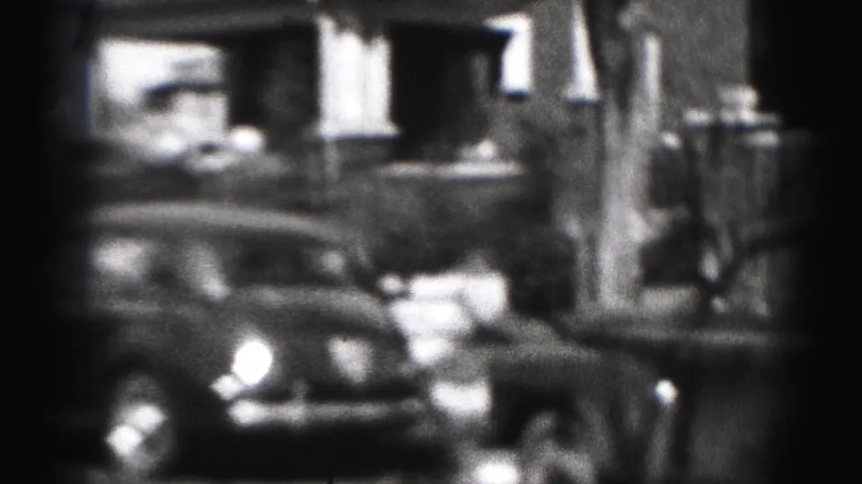 A parked car fills the foreground of a 1975 Harrisburg residential street view, with house fronts and shadows behind it.