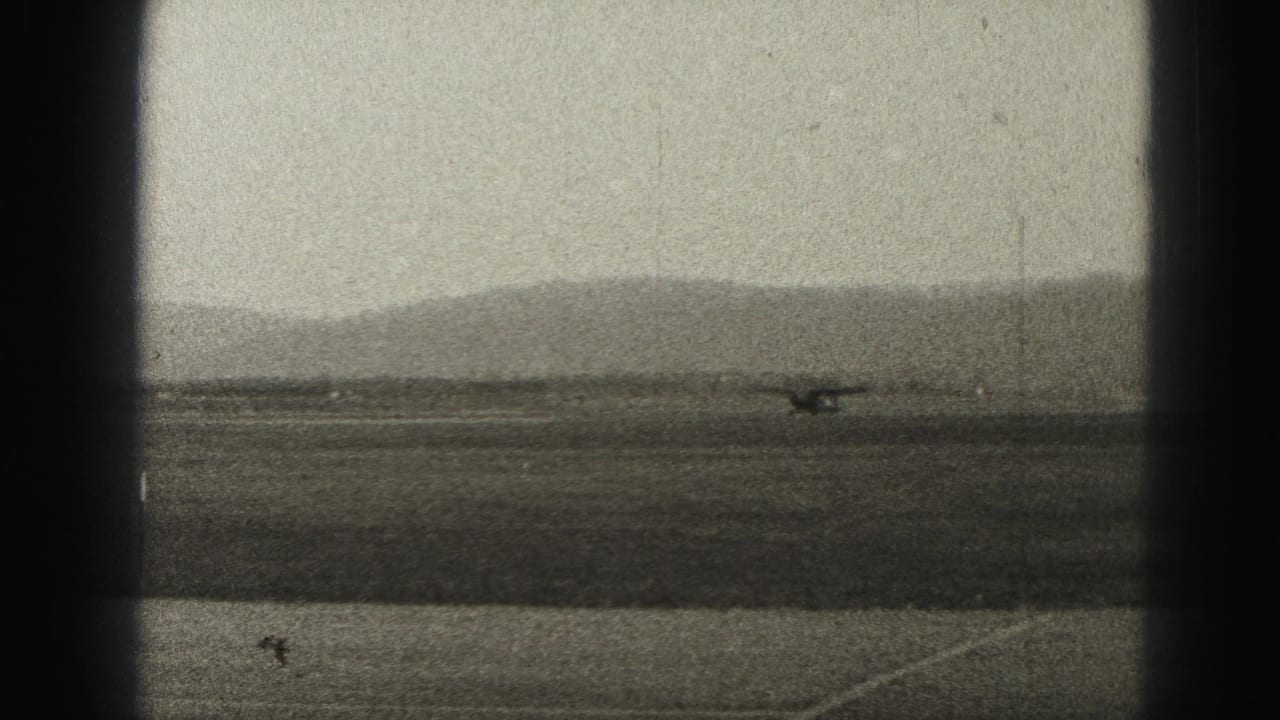 Small propeller plane on a distant runway with hills behind it.