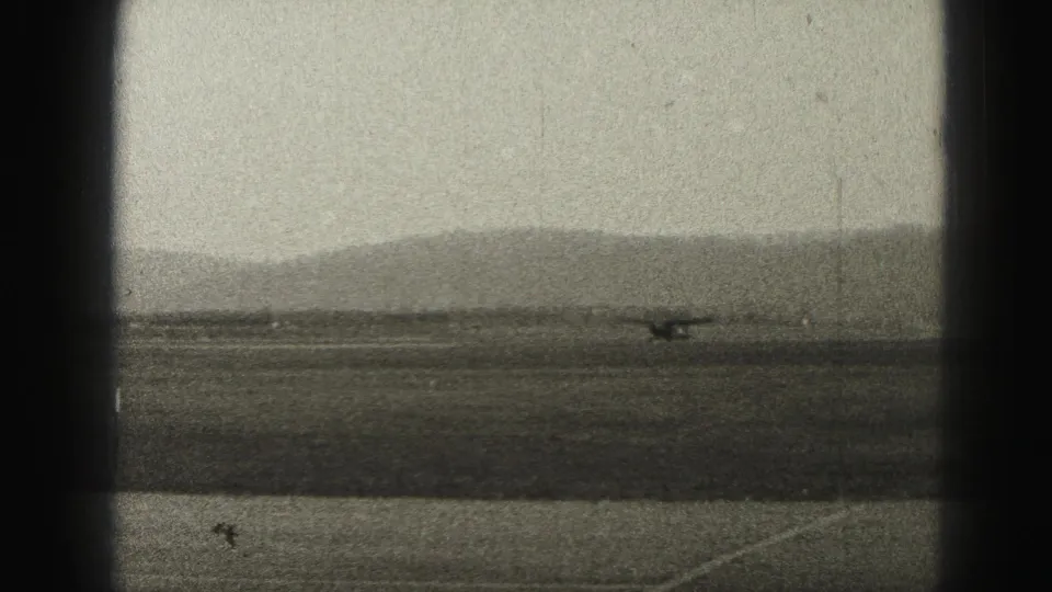 A small propeller plane appears on a runway at a Harrisburg, Pennsylvania airfield in 1975, seen through dark 8mm frame borders.
