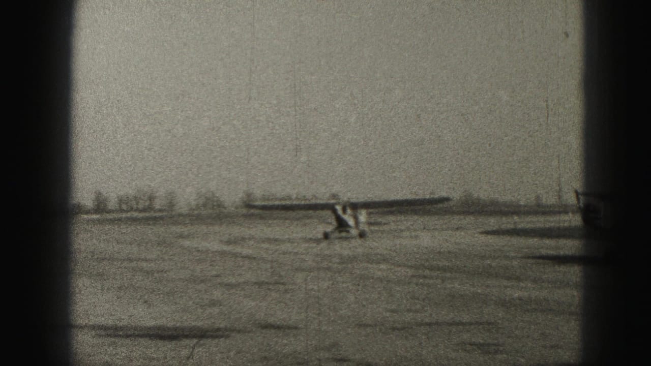 Small light aircraft on a wide paved airfield under an overcast sky.