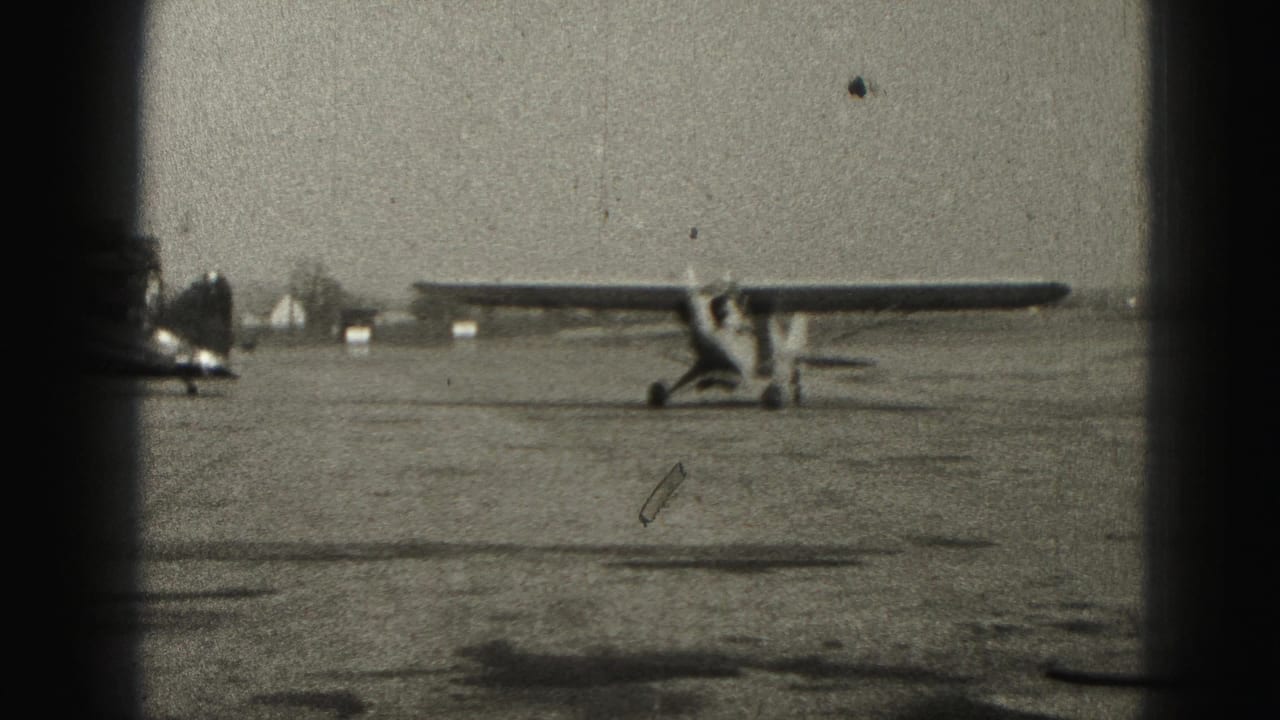 Small single-engine airplane taxiing across a concrete airport apron.