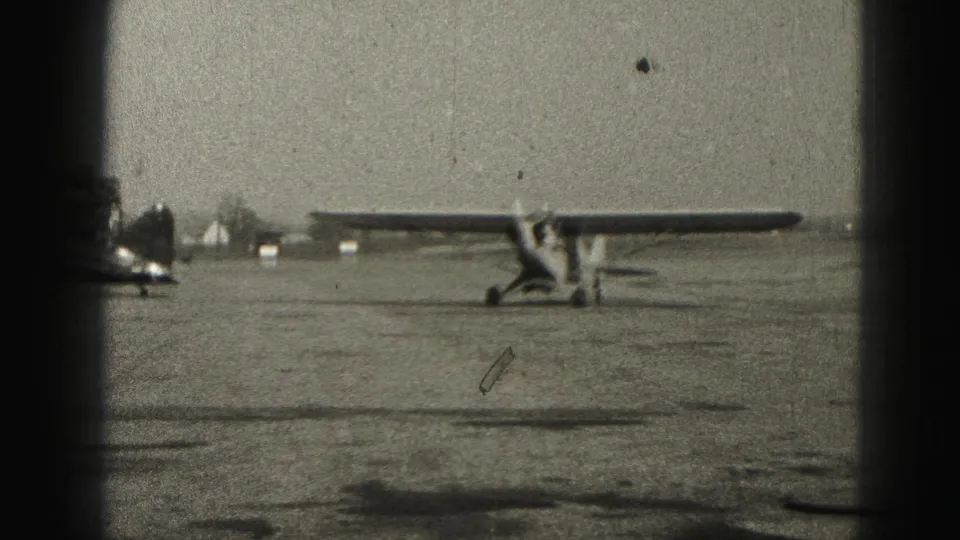 A single-engine monoplane taxis left to right on a Harrisburg, Pennsylvania airport apron in 1975 home-movie footage.