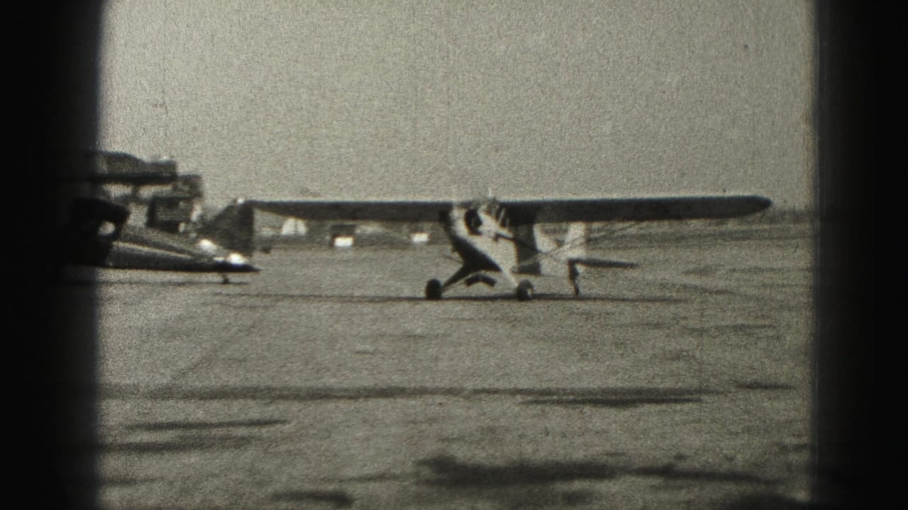 The single-engine airplane continues taxiing past a parked aircraft on the Harrisburg airport apron in 1975.