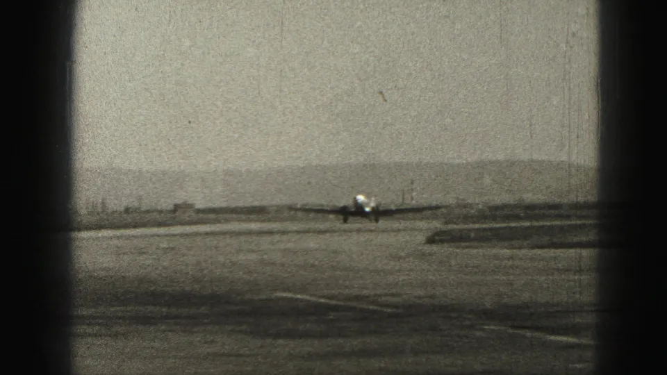 Distant runway view of the small aircraft at Harrisburg, Pennsylvania, in grainy 1975 8mm home-movie footage.