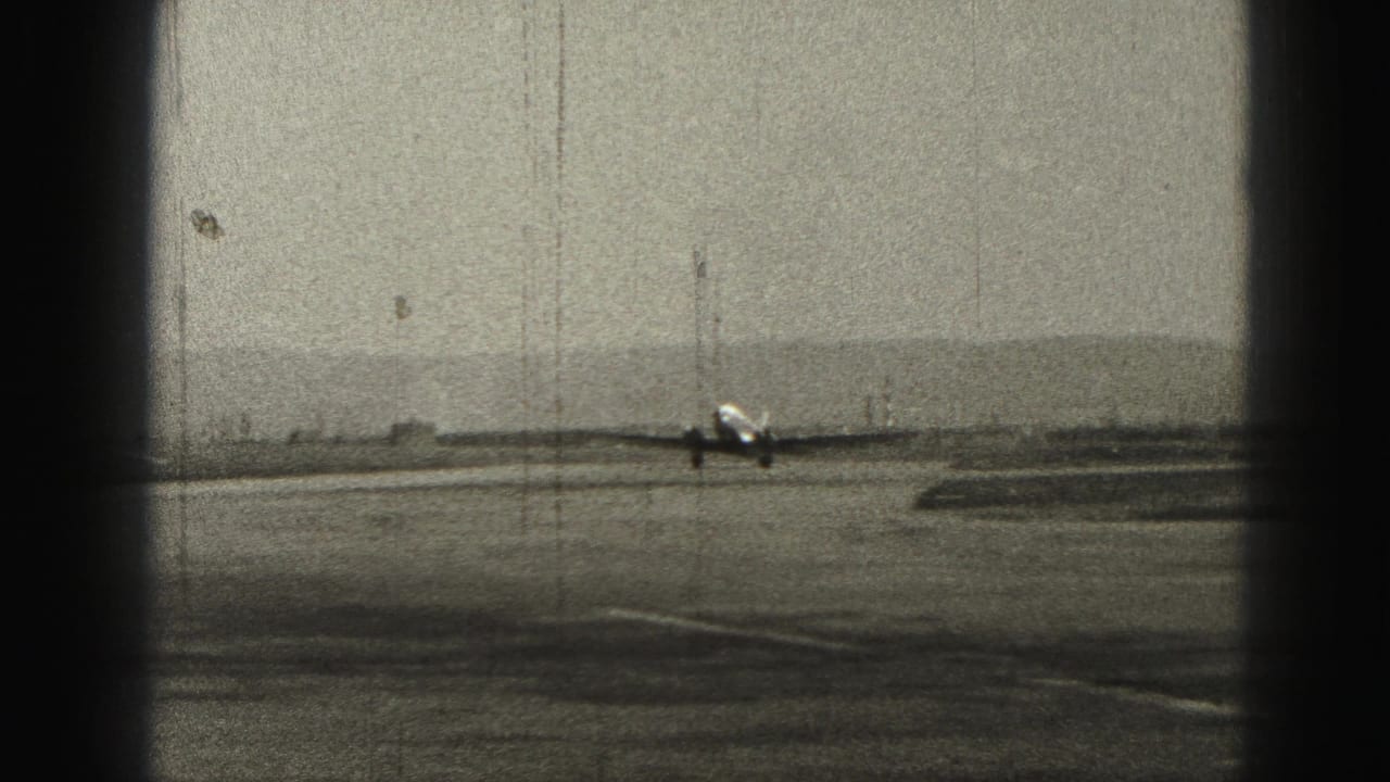 Distant passenger airplane taxiing on a runway under a gray sky.