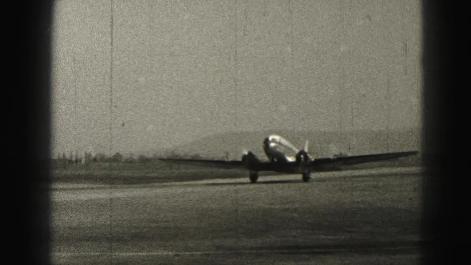 Passenger airplane taxiing across the Harrisburg runway in 1975, framed by dark 8mm contact-sheet edges and a low horizon.