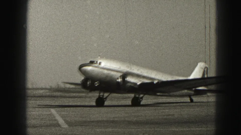 Closer 1975 Harrisburg frame of a propeller passenger aircraft taxiing past the camera on the runway.
