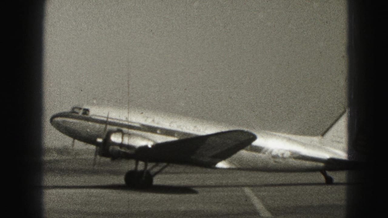A propeller passenger aircraft taxis on the tarmac at Harrisburg, Pennsylvania, seen through dark foreground window divisions.