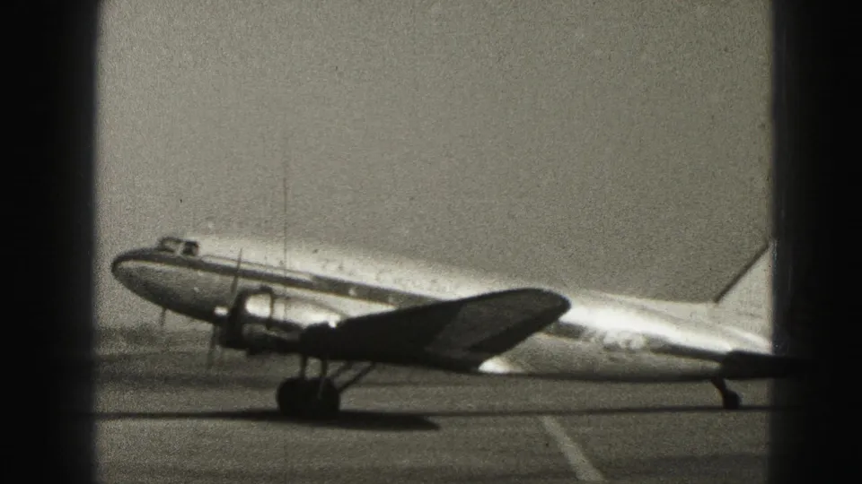 A propeller passenger aircraft taxis on the tarmac at Harrisburg, Pennsylvania, seen through dark foreground window divisions.