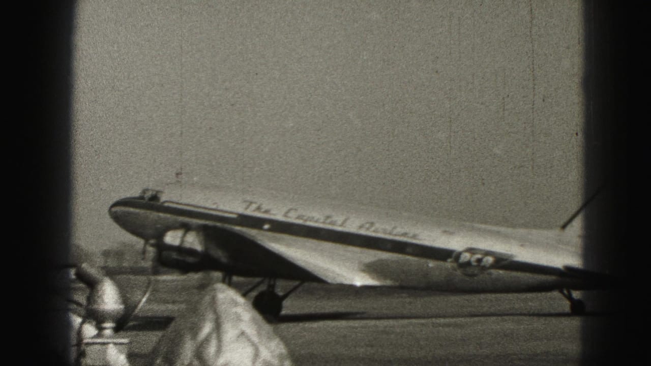 Capital Airlines marked propeller aircraft stands or taxis on the Harrisburg tarmac, partly obscured by terminal-window posts.