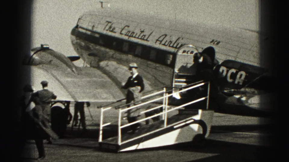 Passengers in coats and hats board a Capital Airlines propeller aircraft by mobile stairs at Harrisburg, Pennsylvania.