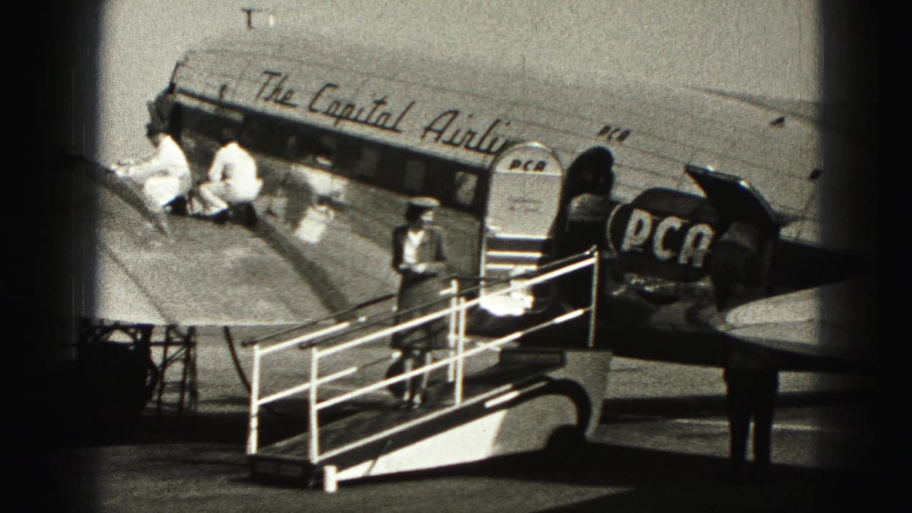Ground crew in white uniforms work near the fuselage as a uniformed attendant stands by mobile stairs at Harrisburg airport.