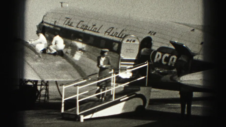Ground crew in white uniforms work near the fuselage as a uniformed attendant stands by mobile stairs at Harrisburg airport.