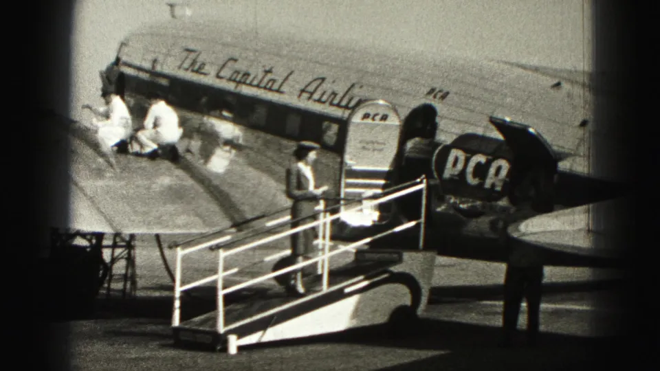 The final frame holds on the mobile stairs, attendant, PCA-marked tail, and aircraft fuselage in Harrisburg airport home-movie footage.