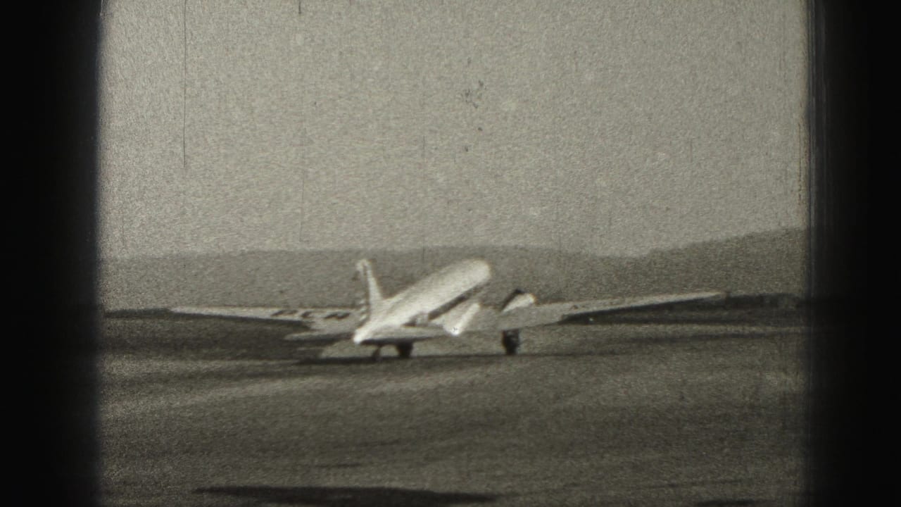 Propeller airplane farther down the runway, viewed from behind and to the side.